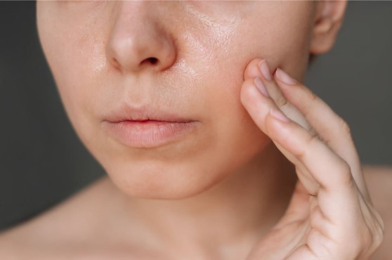 Close-up of a woman touching her cheek, showcasing smooth, glowing skin—ideal for promoting face lifting treatment or skincare procedures targeting firm, youthful skin.