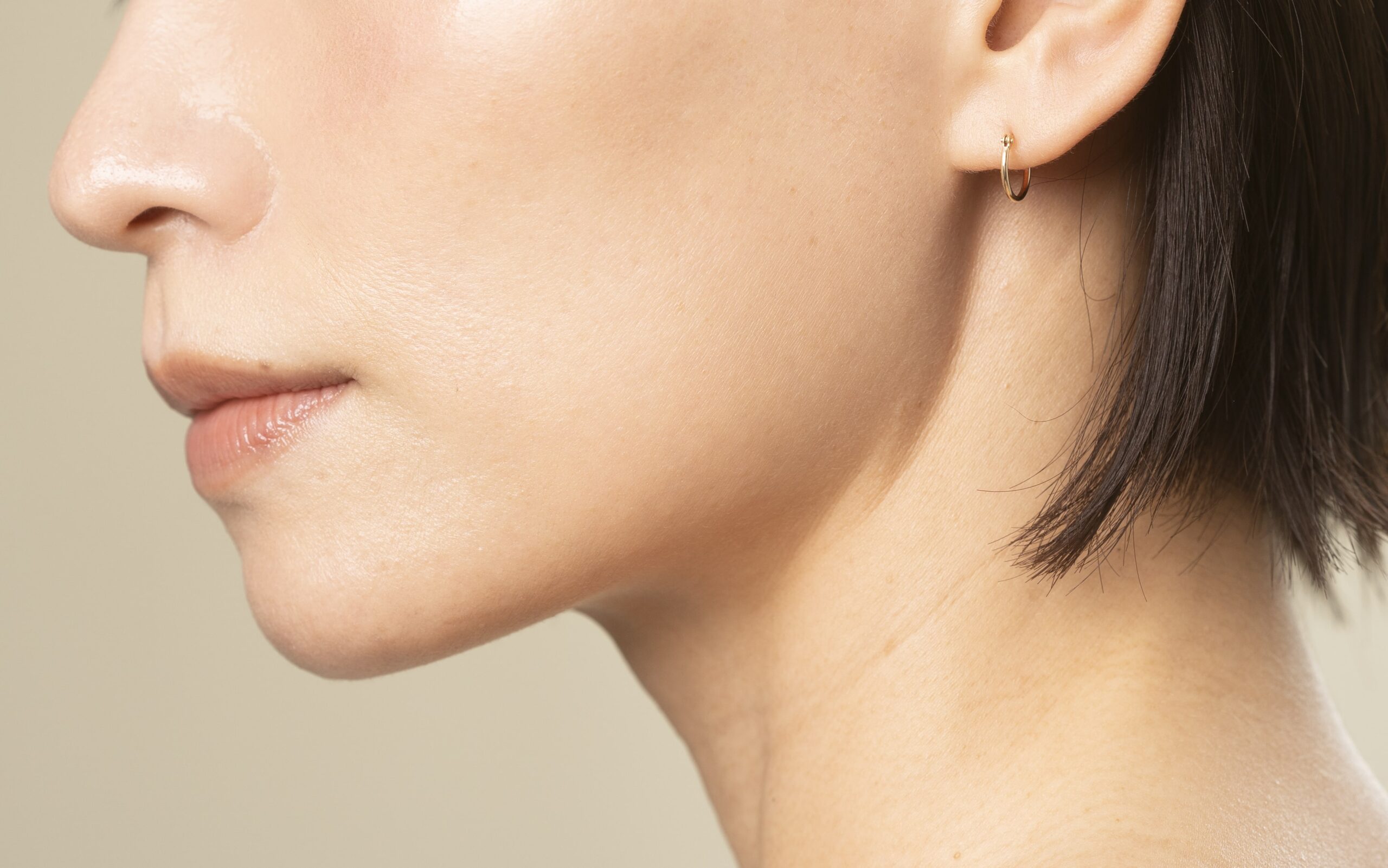 Close-up of a woman's lower face gently touching her cheek, showing clear skin and defined chin—ideal visual representation for chin fillers in Singapore.