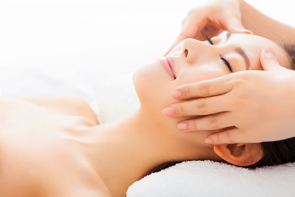Woman lying down during a face lifting treatment, receiving a gentle facial massage to stimulate skin tightening and lift.