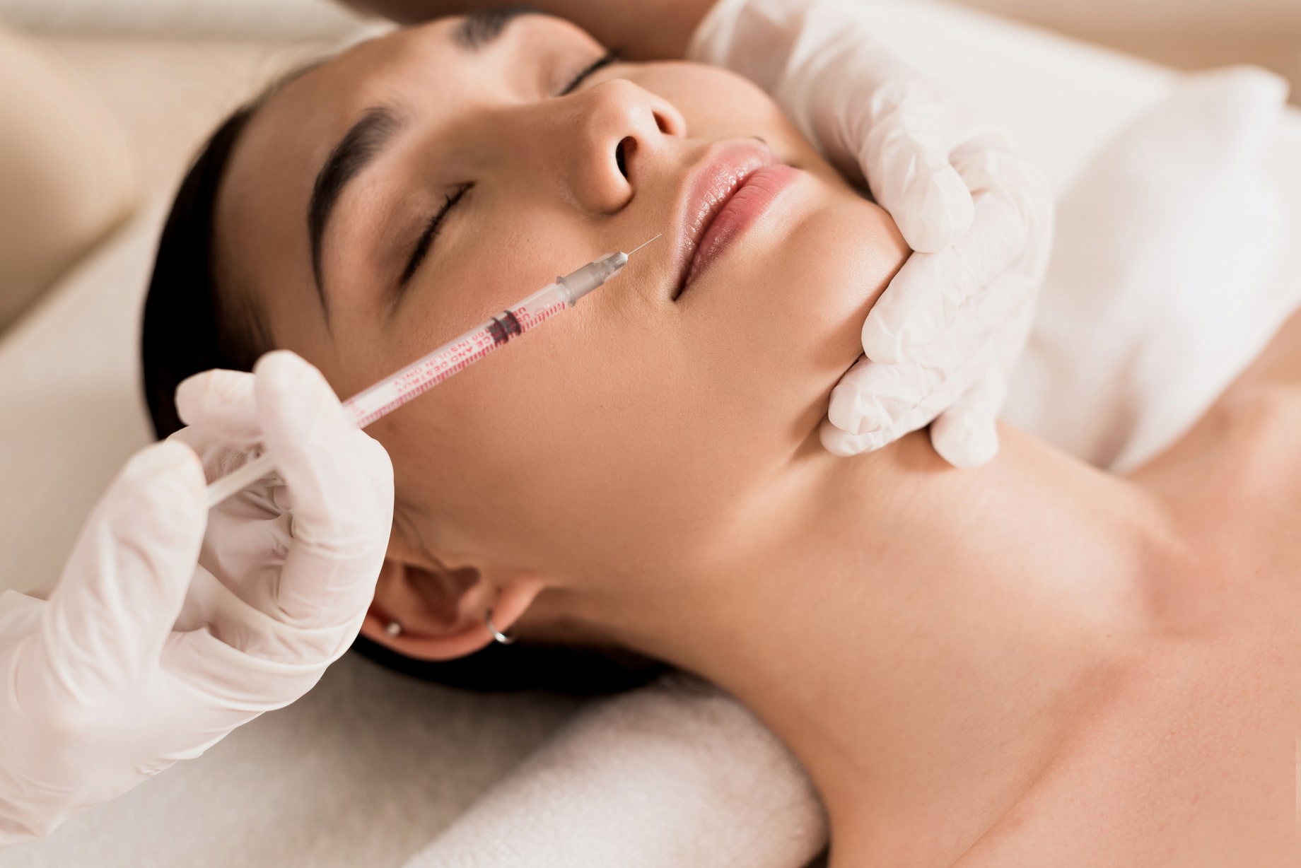 Close-up of a woman receiving a facial injection, illustrating the difference in treatment approaches for HA vs Collagen & Biostimulators.