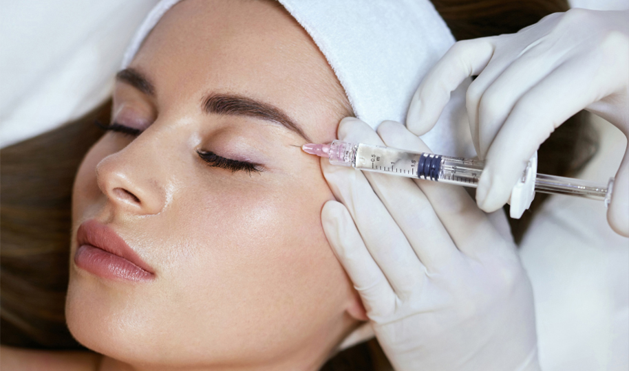 Close-up of an Asian woman's face with an aesthetician administering an injectable filler