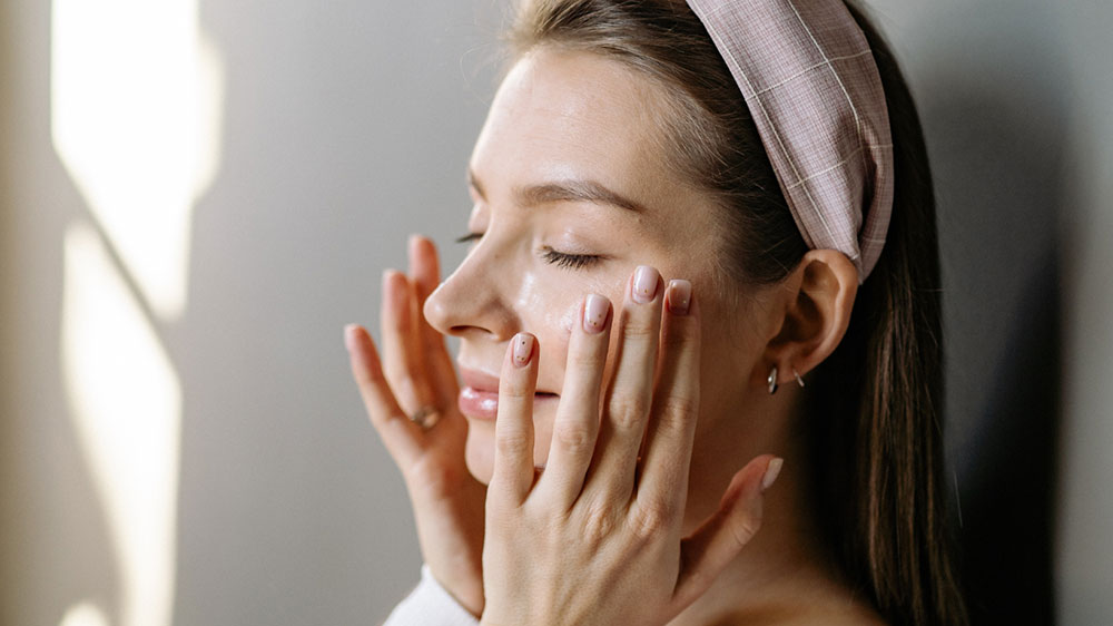 A woman applying topical skincare to prepare the skin barrier and stabilize melanocytes 1–2 weeks before laser treatment.