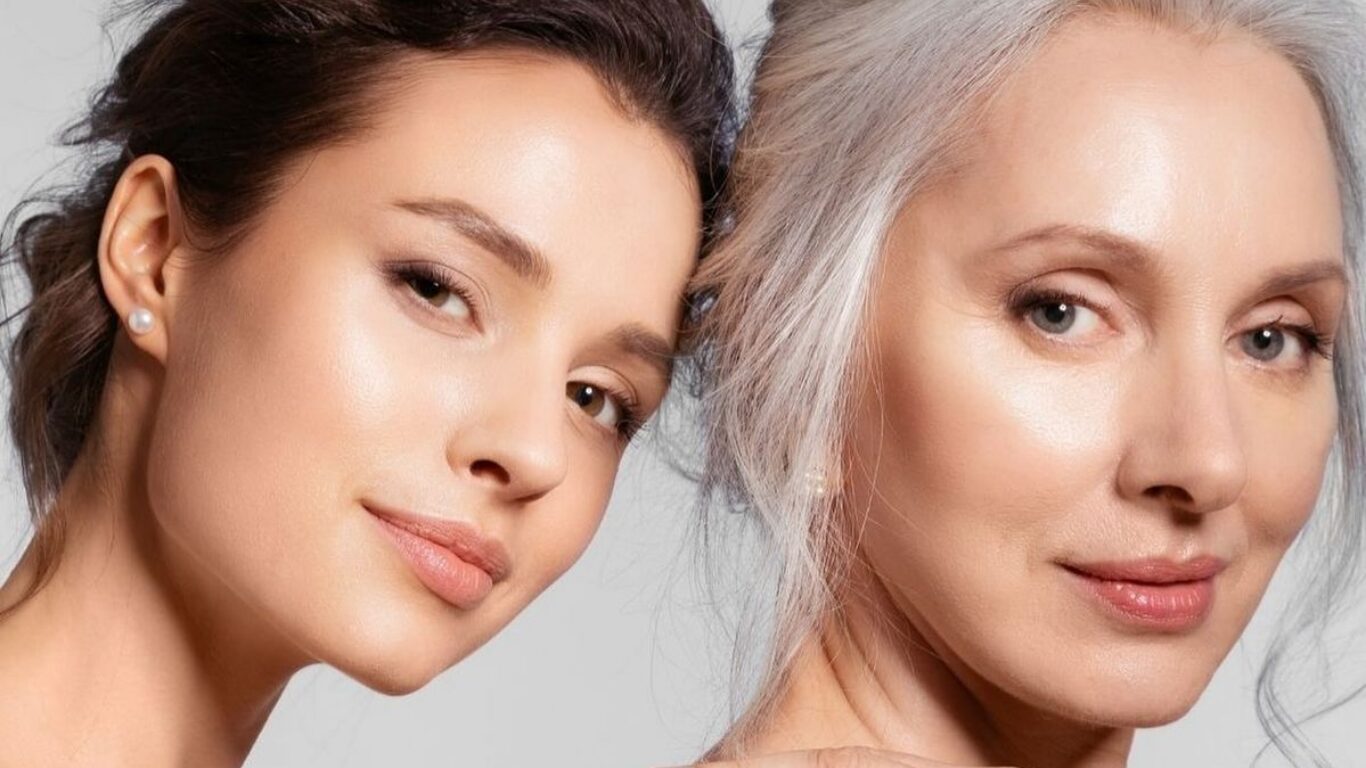 A younger woman and a mature woman with grey hair posing together, reflecting aging as a natural evolution