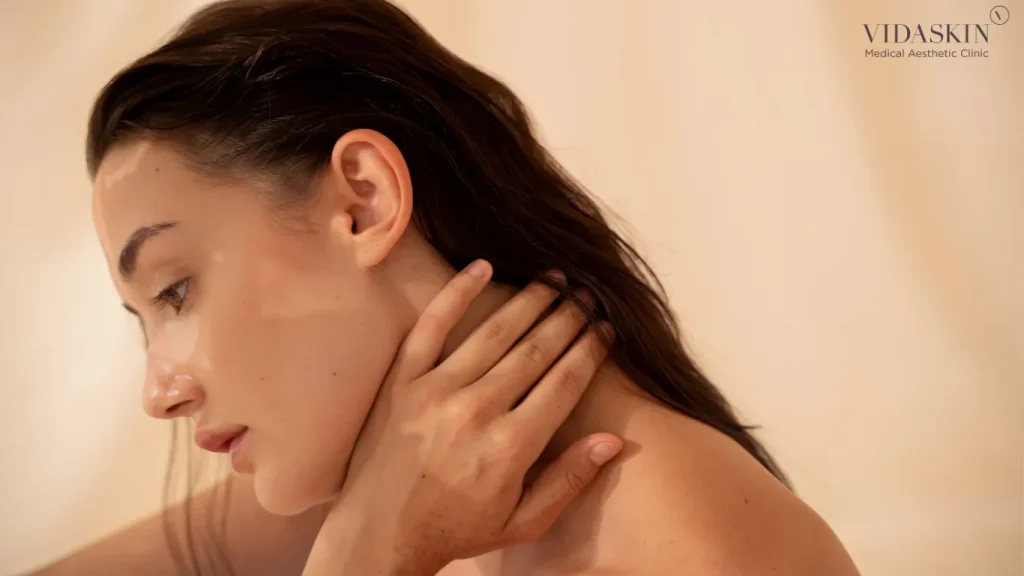 Side view of a woman holding her neck